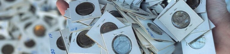 Hand holding a collection of coins in holders, showing the consideration of whether to clean coins prior to sale.