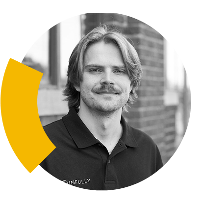 Braden French, a man with medium-length hair and a mustache, smiles in front of a brick wall.