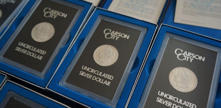 Carson City uncirculated silver dollar coins displayed in protective cases with blue backgrounds.