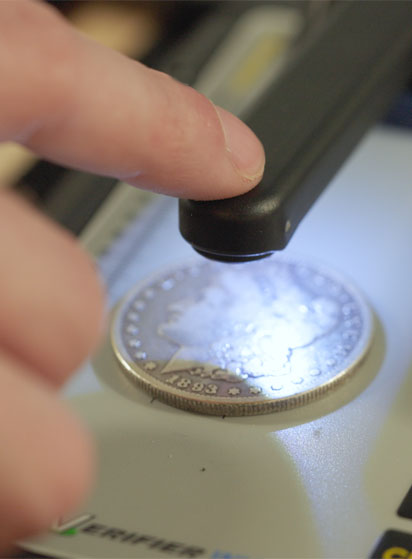 Close-up of a coin being examined under a magnifying glass.